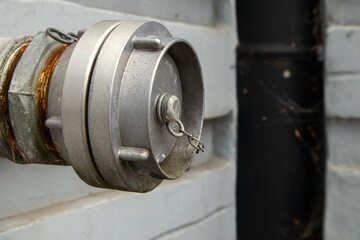 Old metal fire hydrant pipe with weathered cap and rust detail on an industrial wall