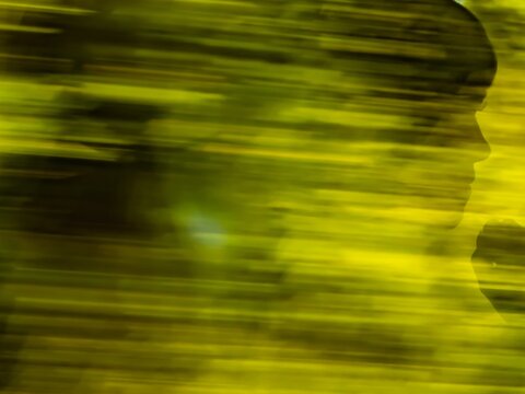 Abstract artistic photo of human silhouette in motion blur with green and yellow tones, expressing thought, contemplation and mystery