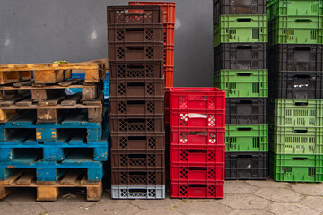 Stacked plastic crates and wooden pallets in a warehouse yard, colorful containers for transport, logistics, and storage industry background