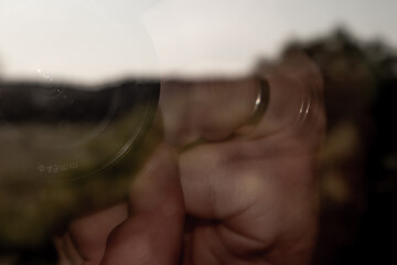 Abstract image of hand with ring and camera lens reflection on glass surface. Blurred, mysterious, conceptual photo with creative motion blur