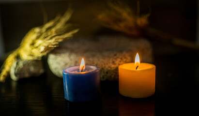 Velas encendidas sobre superficie oscura con decoración rústica y fondo desenfocado