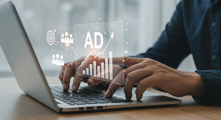 A person types on a laptop with digital advertising and marketing graphics displayed