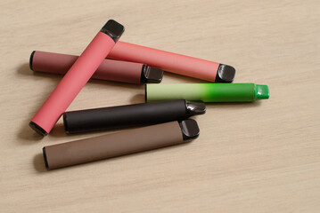 Various disposable electronic cigarettes on light table background