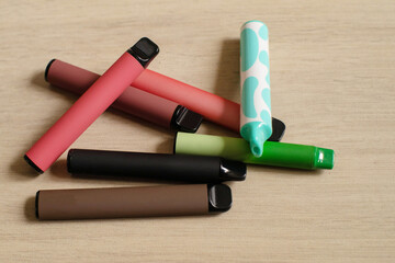 Various disposable electronic cigarettes on light table background