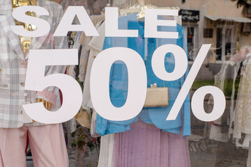 Sale 50% written on the glass of a clothing store window