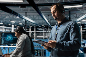 Data center system administrator using headset mic, providing remote diagnostics using tablet....