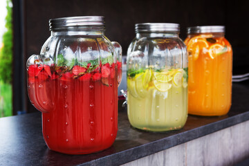 Assortment of lemonades and cool natural drinks in jars with ice on the counter at a stand in the park. Selling food products at a street fair. Street food to go. Fast food.	