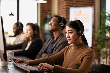 Asian employee reviewing customer feedback on a desktop pc, strategizing ways to improve service...
