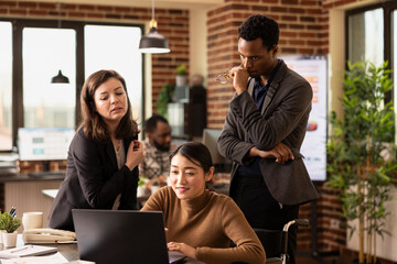 Injured asian woman in wheelchair, businessman and female entrepreneur engage in a discussion about financial analytics. Coworkers working on strategy ideas in startup office, using a laptop.
