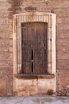 Ventana antigua de madera con reja met&aacute;lica sobre fachada de adobe en Autl&aacute;n, Jalisco, M&eacute;xico.
