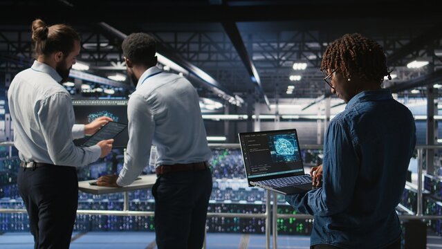 Data center system administrators collaborating to maintain servers using artificial intelligence. Teamworking colleagues doing infrastructure AI machine learning automatization,