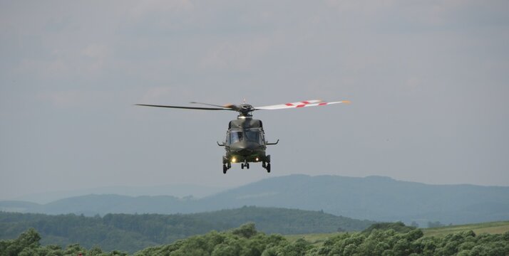 military transport helicopter with its landing gear down hovered over the ground as it approaches for landing