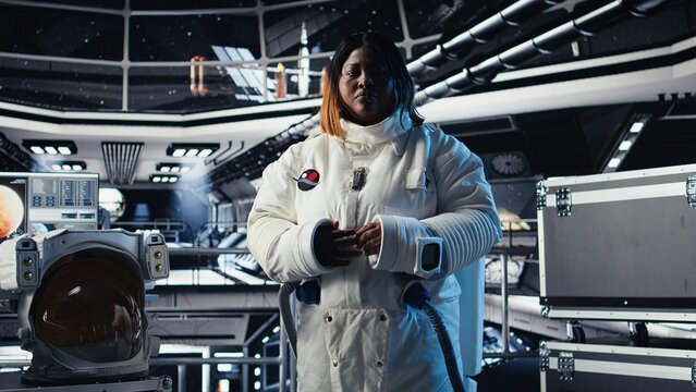 Happy female astronaut saluting command center researchers during videocall, sharing recent discoveries. African american woman in spaceship provides scientific findings to Earth team