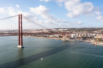 Boat crossing the 25 de abril bridge in Lisbon, Portugal.
