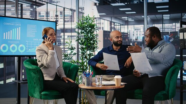 Woman business leader interrupting a meeting for an insightful phone call, discussing some important details on the telephone line. Diverse ambitious CEOs during a conference. Camera A.