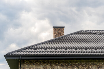 New Home Construction Showing Roof Tiles and Brick Chimney Stack Against Overcast Sky
