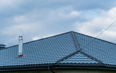 Rooftop showcasing a house with metal roofing tiles and a steel chimney