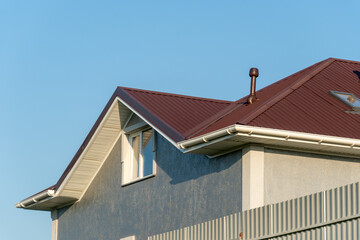 Modern House Exterior with Red Corrugated Metal Roof and Clear Blue Sky