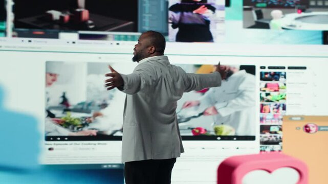 Overjoyed man with open arms facing large digital video wall expressing happiness, benefiting from endless entertainment selection. Joyful viewer enjoying access to endless streaming options, camera A