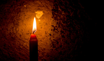 Vela roja encendida sobre fondo rústico oscuro, iluminación cálida y ambiente íntimo