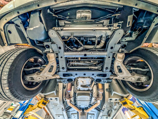 under sedan vehicle on a car lift in auto shop