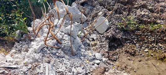 Construction Debris Piles Alongside Green Vegetation and Muddy Ground in Urban Development Area