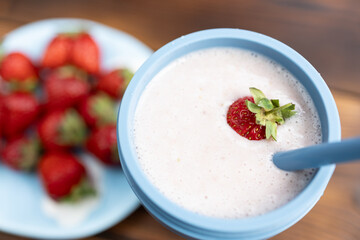 A glass of strawberry milkshake. Pink peonies and red strawberries