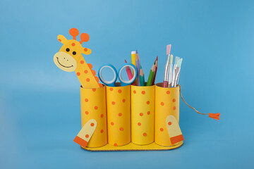 Creative pencil holder with giraffe face and tail made from recycled paper rolls, filled with...