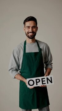 Commer&ccedil;ant souriant en tablier vert avec pancarte OPEN