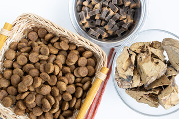 There are different kinds of pet treats in the bowl. Crispy breakfast cereals, chewing gums and pieces of dried meat. For the care of pets and their proper nutrition.