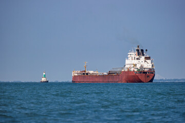 Great Lakes freighter heading toward a lighthouse