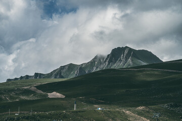 Dramatic mountain landscape with rocky peaks and cloudy sky, remote green valley, nature wilderness, hiking destination, adventure background.