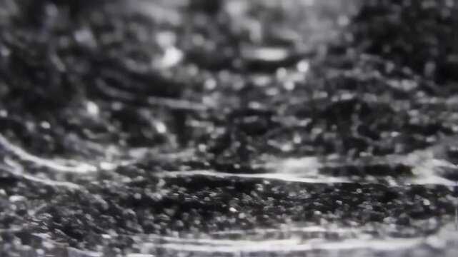 Tiny black ferromagnetic particles shift and ripple in a mesmerizing dance, forming dynamic, textured landscapes in an abstract closeup.