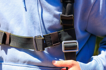 Close-up of climbing harness on person wearing blue hoodie outdoors