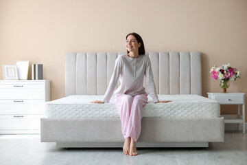 Woman on bed with orthopedic mattress at home