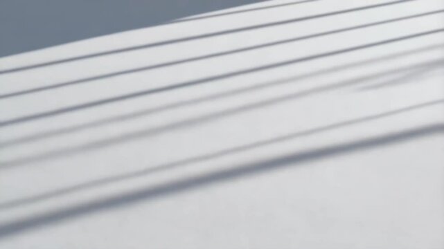 Abstract shot of parallel shadows falling diagonally on a white textured surface creating a clean and minimalist design.