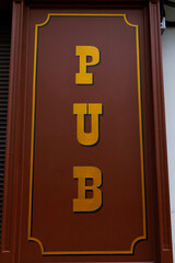 An Eye-Catching Pub Sign Featuring Bold Letters and a Striking Color Contrast of Brown and Yellow for a Warm and Inviting Atmosphere.