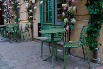 Charming Outdoor Cafe Setting with Green Chairs and Floral Decorations by the Entrance, Perfect for...