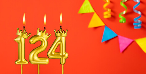 Number 124 birthday candle on an orange background with pennants