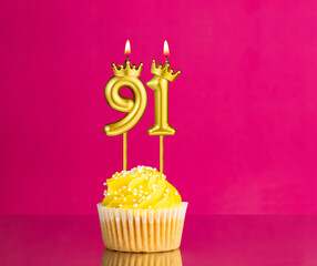 Birthday celebration with number 91 candle - Yellow cupcake on a pink background