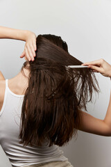Fototapeta premium Hair care, grooming, young woman combing hair, healthy long hair, minimalist background, white backdrop, casual style, beauty routine, attention to hair texture, personal care, satisfaction