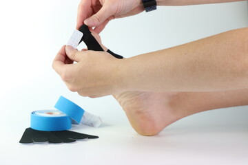 Woman foot with a kinesiology tape in black to recovery a foot sport pain