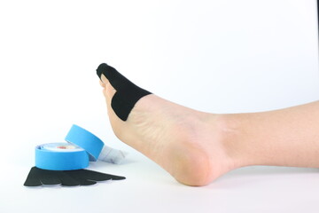 Woman foot with a kinesiology tape in black to recovery a foot sport pain