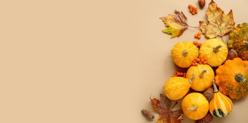 Pumpkins, acorns, berries and autumn leaves on beige background with space for text