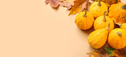 Pumpkins and autumn leaves on beige background with space for text