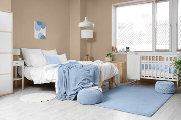 Interior of light room with big bed, baby crib and window