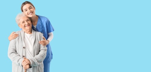 Nurse hugging senior woman on blue background with space for text