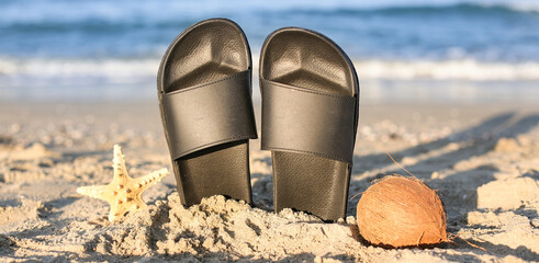 Stylish female flip flops, starfish and coconut on sand