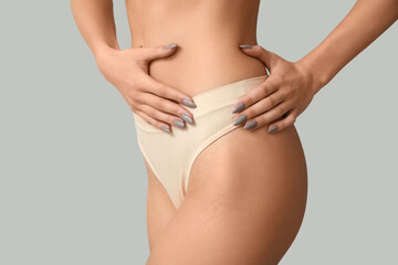 Young woman on panties on light background, closeup. Plastic surgery concept
