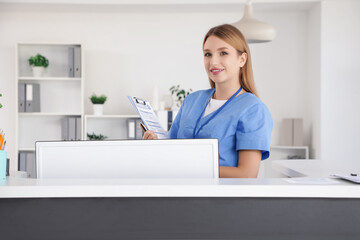 Female medical intern with clipboard at reception in clinic